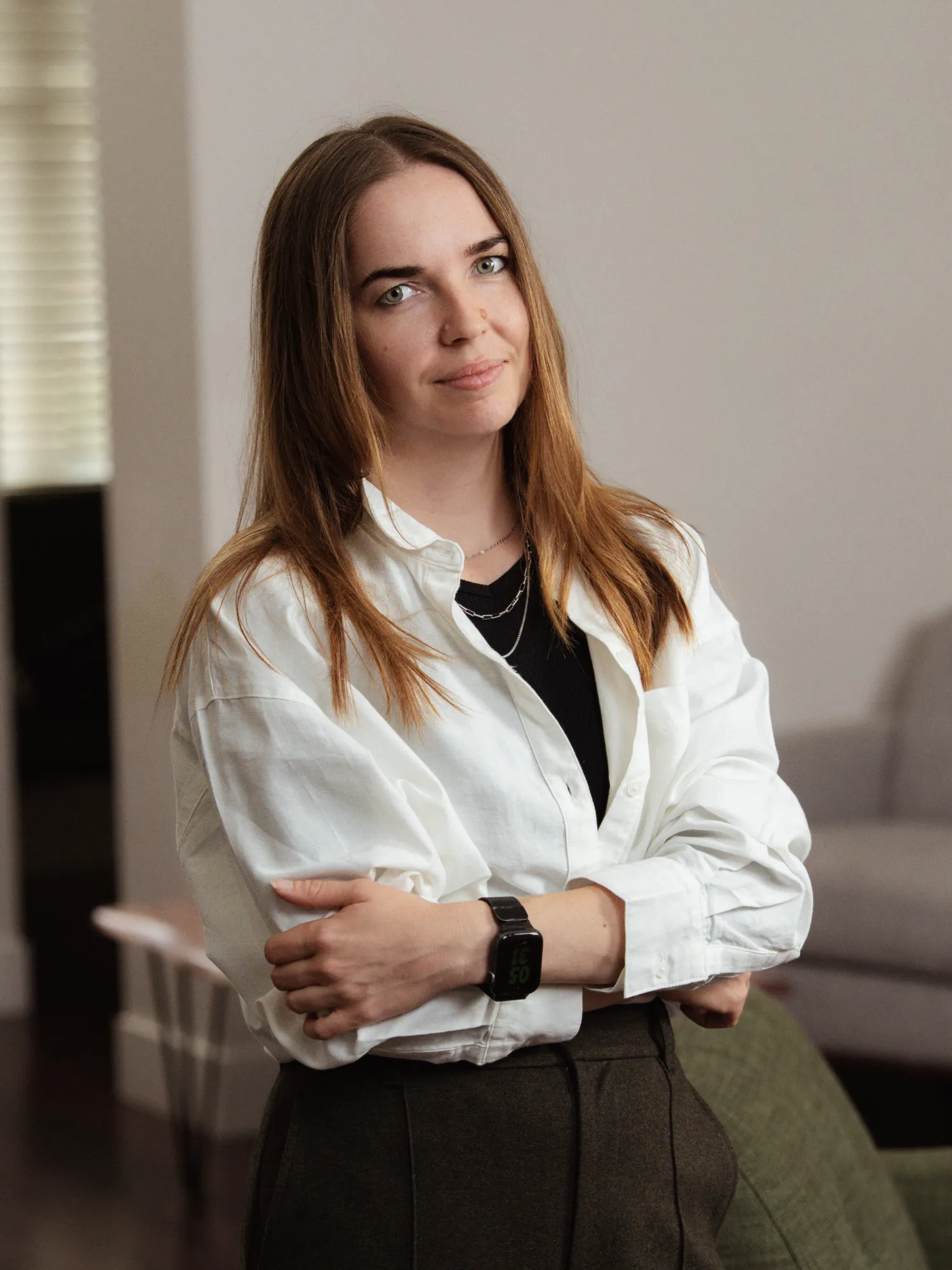 Portrait of Ksenia standing indoors in a white shirt with her arms folded