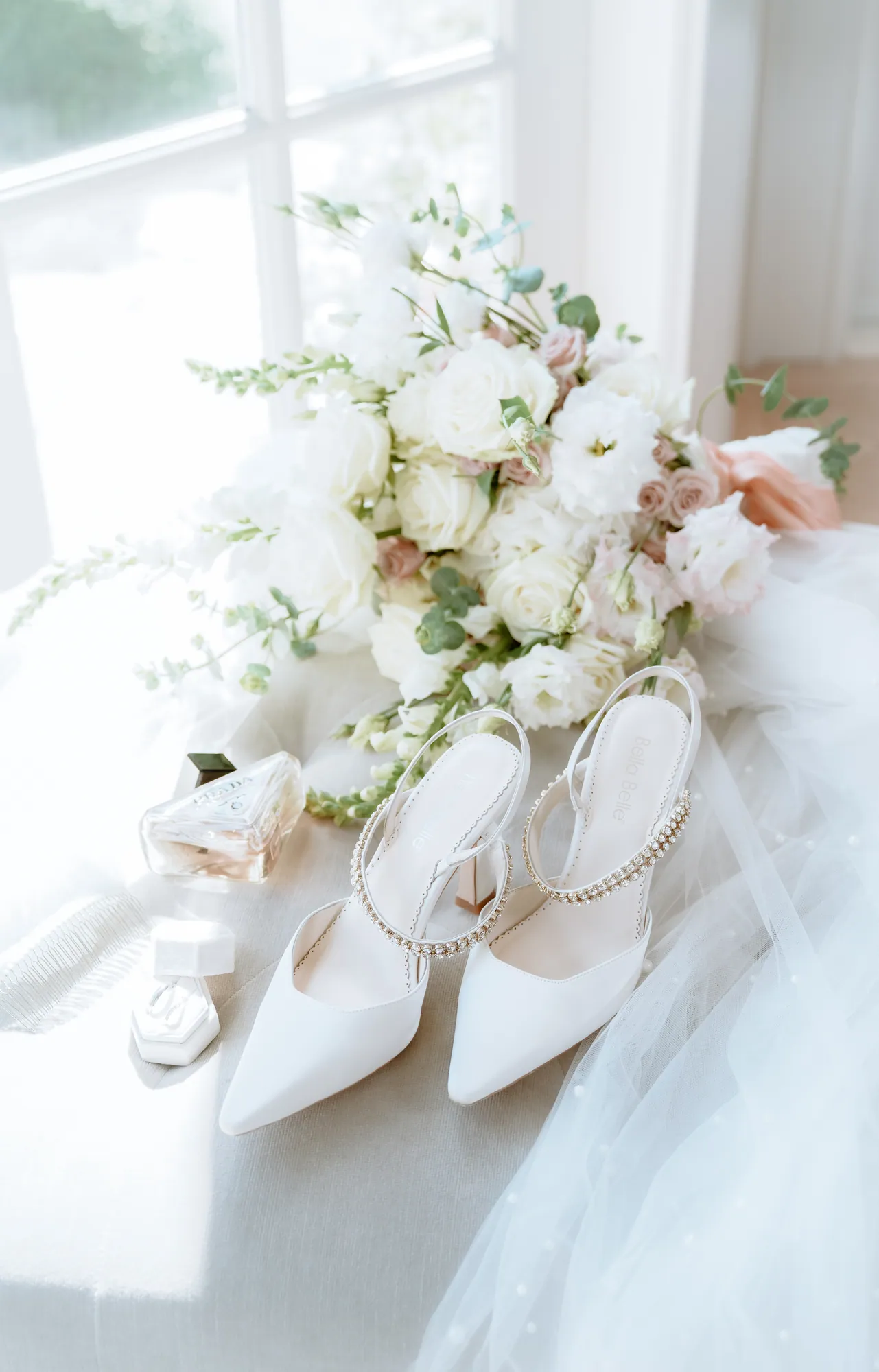 A pale bouquet and the bride's shoes arranged in soft window light