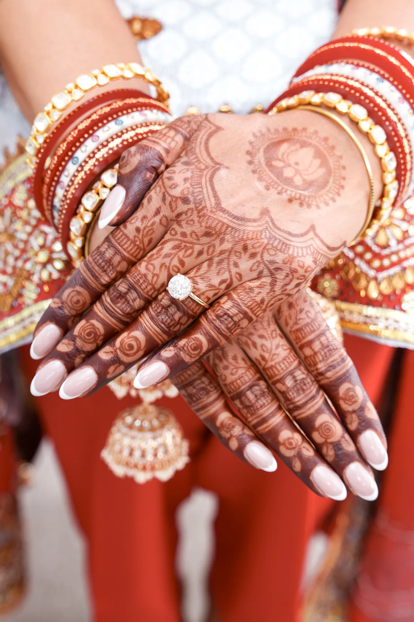 Hands decorated with intricate henna, wearing gold and red bangles